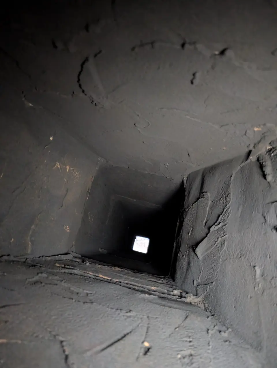 Looking up a masonry flue lined with creosote before cleaning
